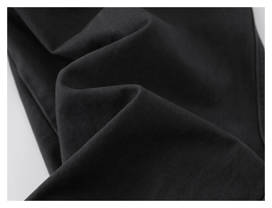 Close-up of black trouser fabric draped to show its surface and folds.
