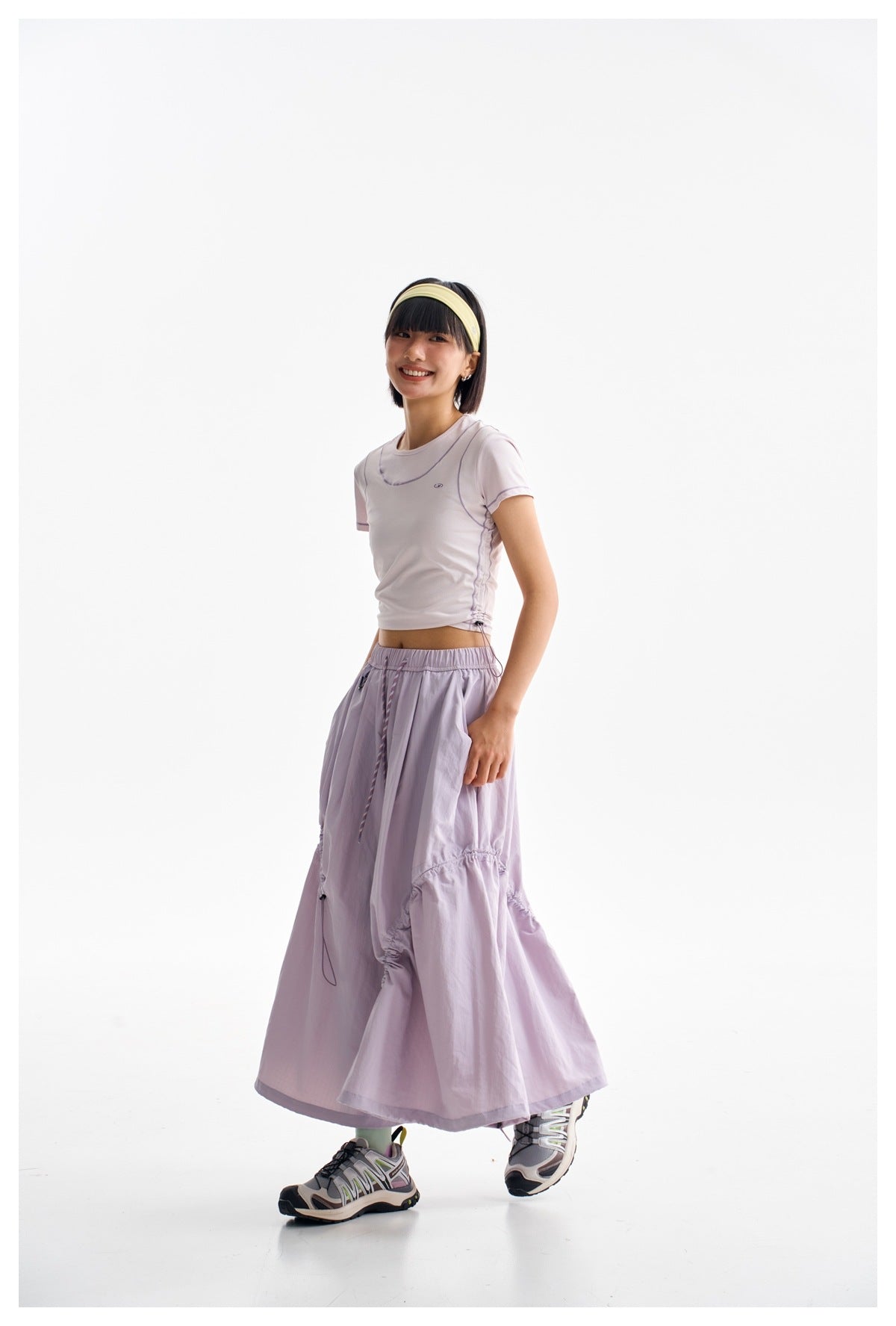 Three-quarter side view of a model wearing a pale lilac cropped T-shirt and matching long gathered skirt.
