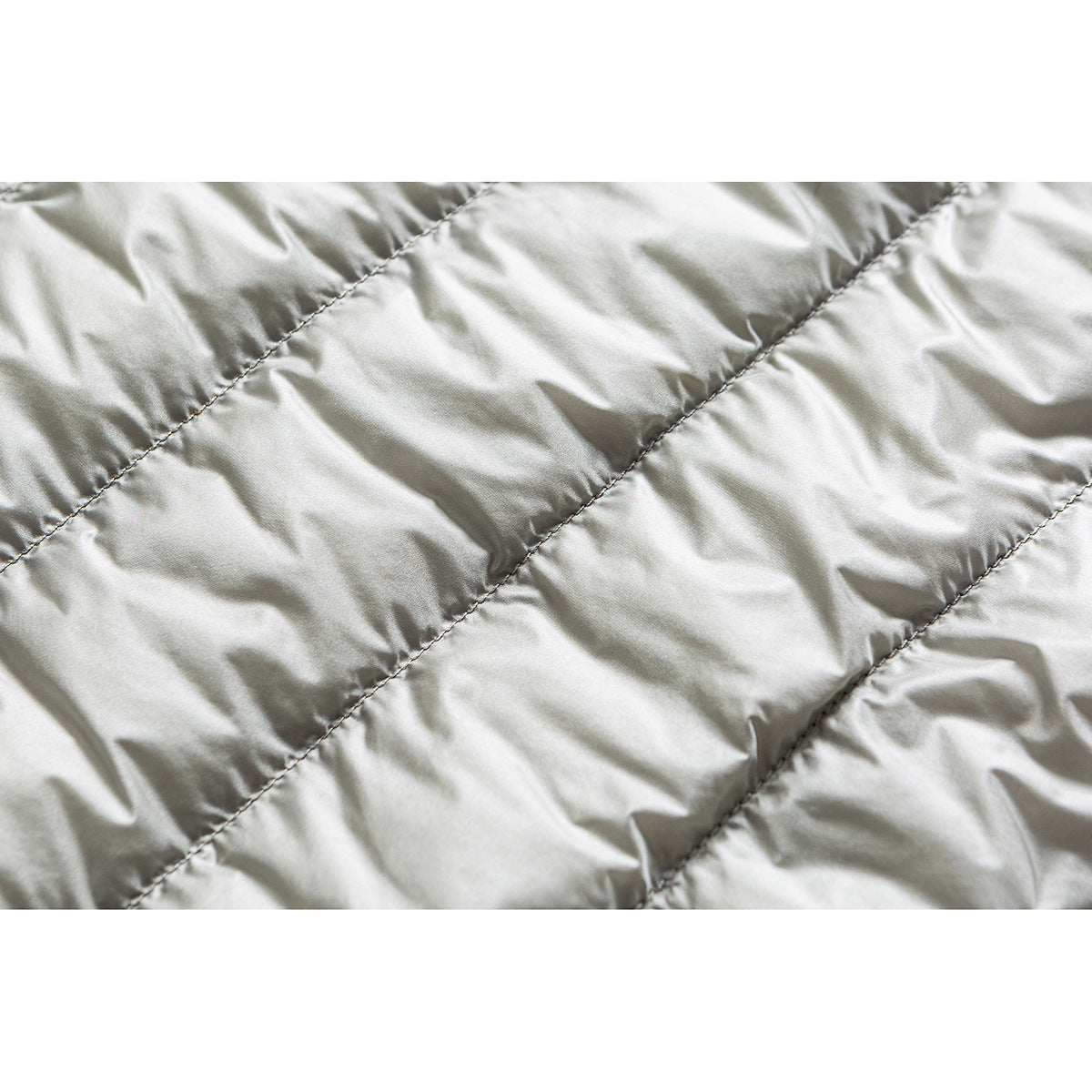 Close-up of light gray padded jacket lining with diagonal stitched channels.