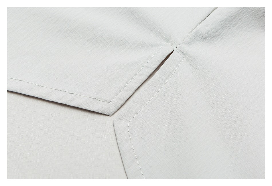 Close-up of pale gray fabric panels meeting at a stitched corner, showing folded edges and fine grid texture.