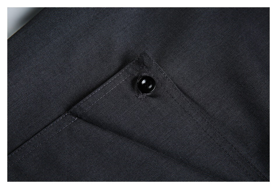 Close-up of charcoal trouser fabric and a triangular buttoned flap with visible stitching.