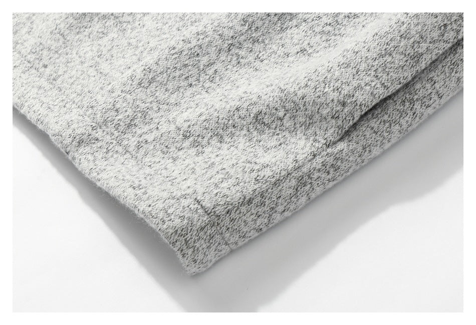 Close-up of a folded hem on light gray marled knit fabric.