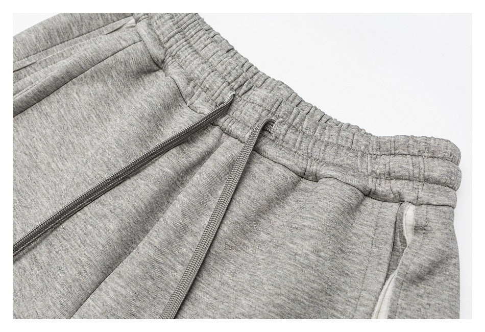 Close-up of gray heathered pants with a gathered elastic waistband, drawstring, and pocket opening.
