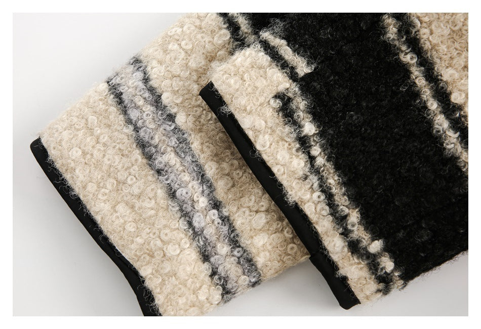 Close-up of black trim and a narrow welt pocket on the cream, gray, and black striped jacket.