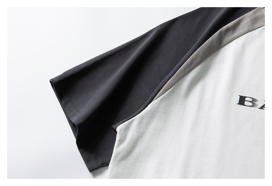 Close-up of the charcoal sleeve and white body of a raglan T-shirt, with part of its black print visible.