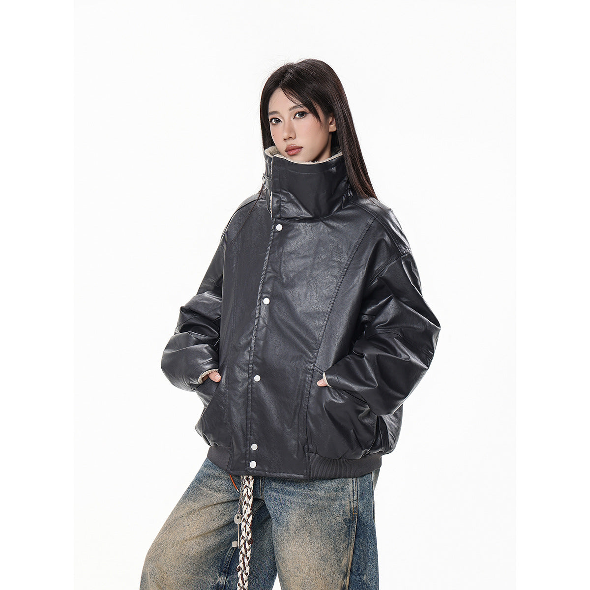 Model wearing an oversized black glossy jacket with a tall collar, silver snaps, and ribbed hem.