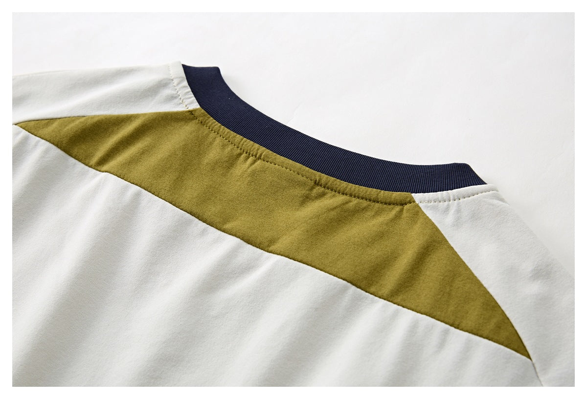 Close-up of the shirt's navy ribbed crew neck and mustard shoulder panel on ivory fabric.
