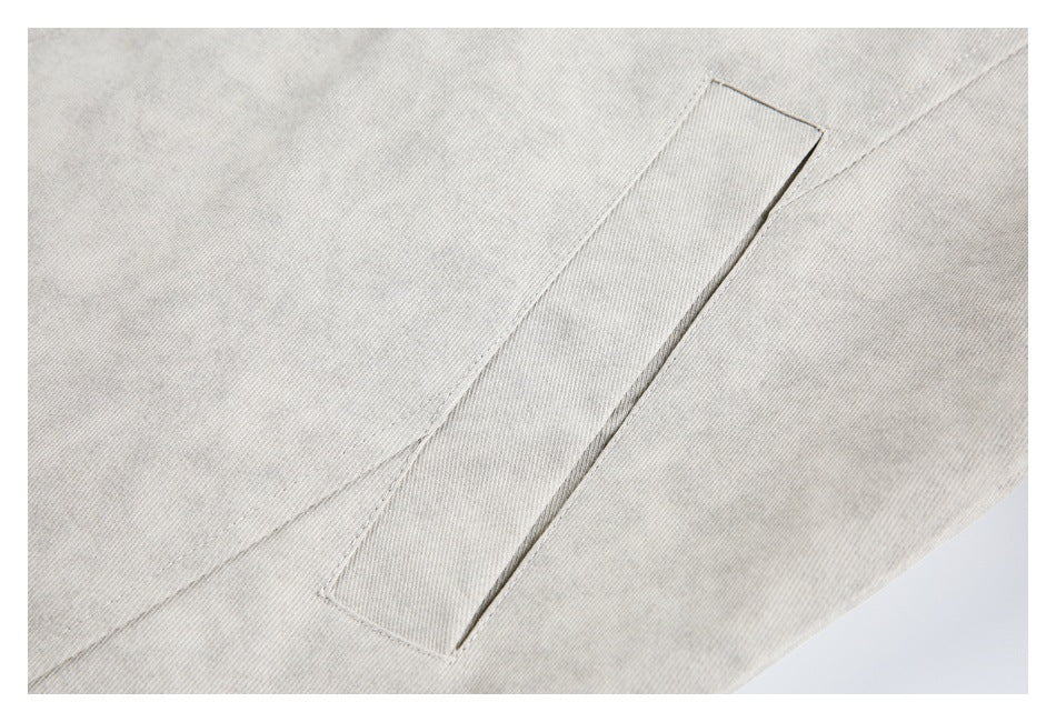 Close-up of a slanted welt pocket on a light gray jacket.