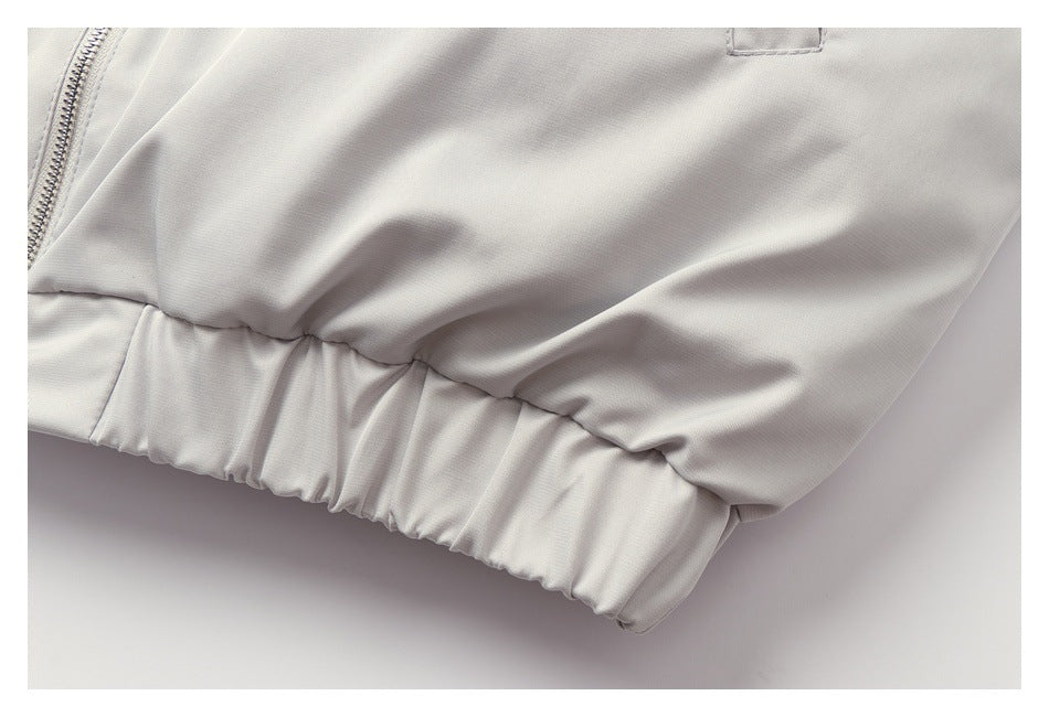 Close-up of the gathered elastic hem on a light gray jacket.