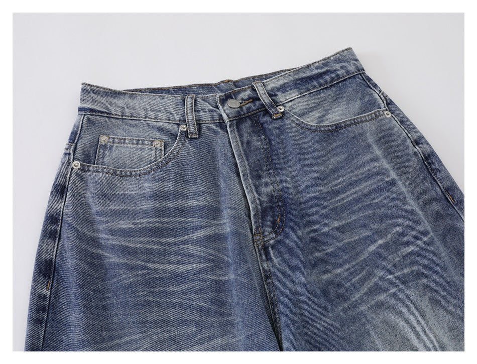Close-up of the jeans' front waistband, button, fly, belt loops, and faded whiskering across the hips.