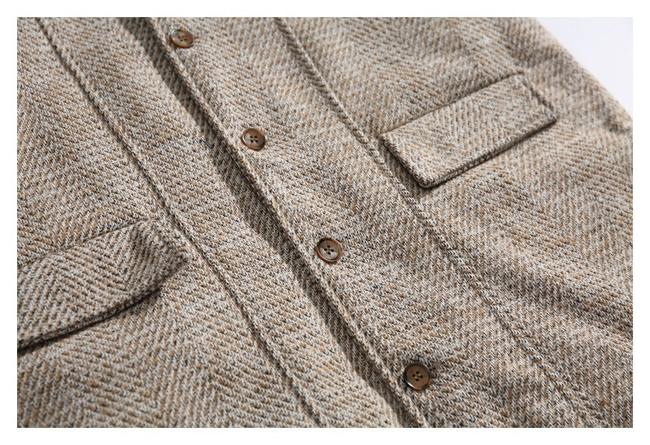 Cropped front view of a tan and cream herringbone tweed coat with brown buttons and flap pockets.