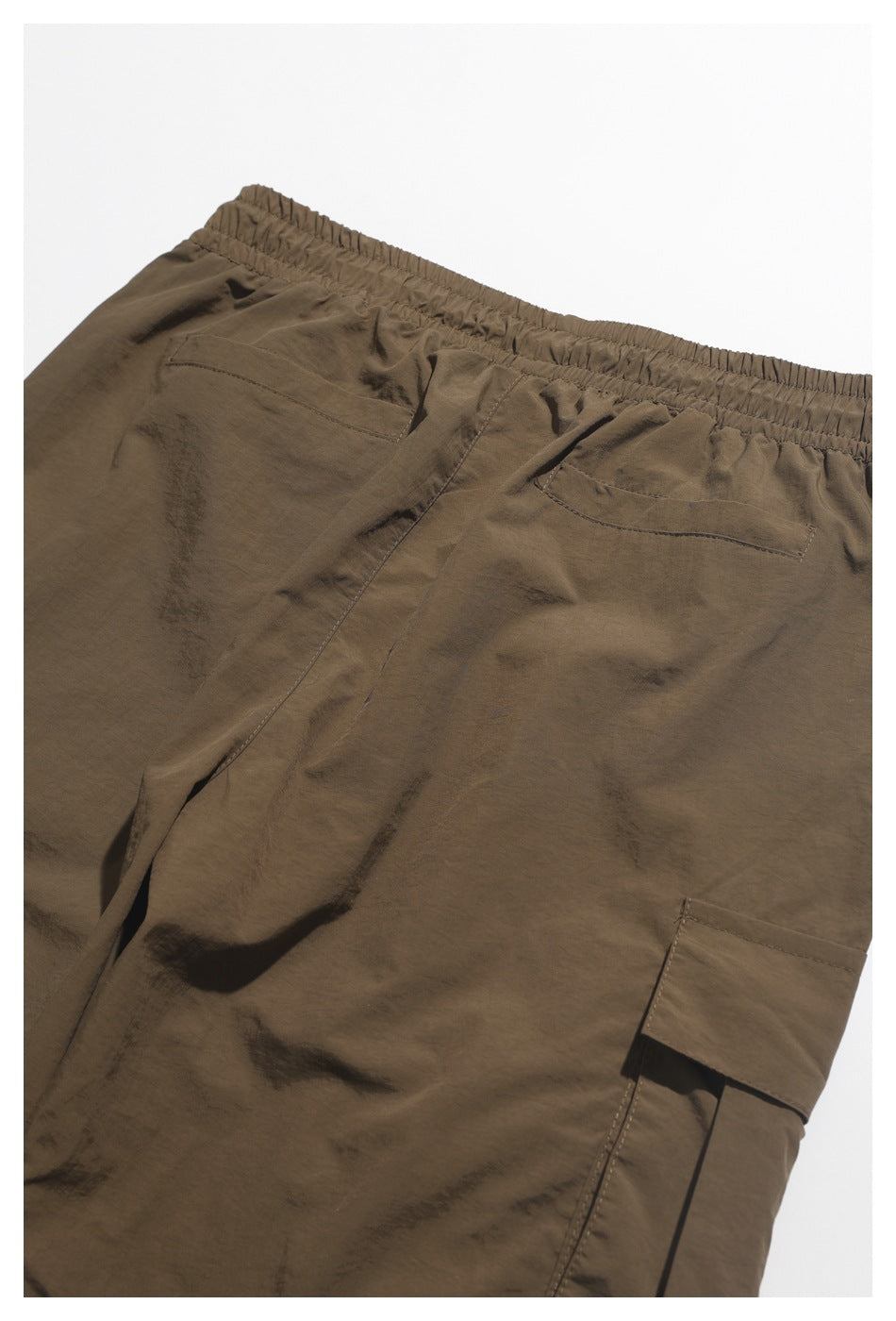 Cropped rear view of brown shorts with an elastic waistband, two back pockets, and a side cargo pocket.