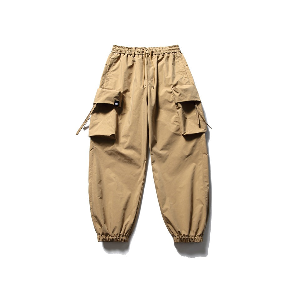 Khaki cargo jogger pants with elastic drawstring waist, large flap pockets and gathered cuffs, flat lay on white