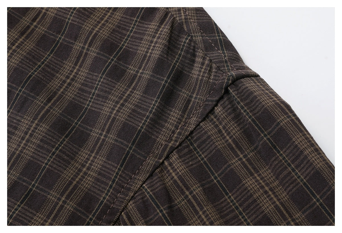 Close-up of the shoulder seam and sleeve on a dark brown plaid shirt.