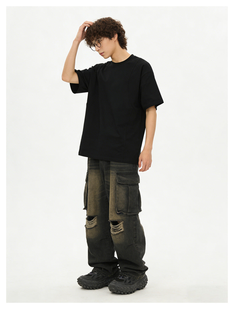 Model wearing a black oversized short-sleeve T-shirt and distressed dark cargo pants.