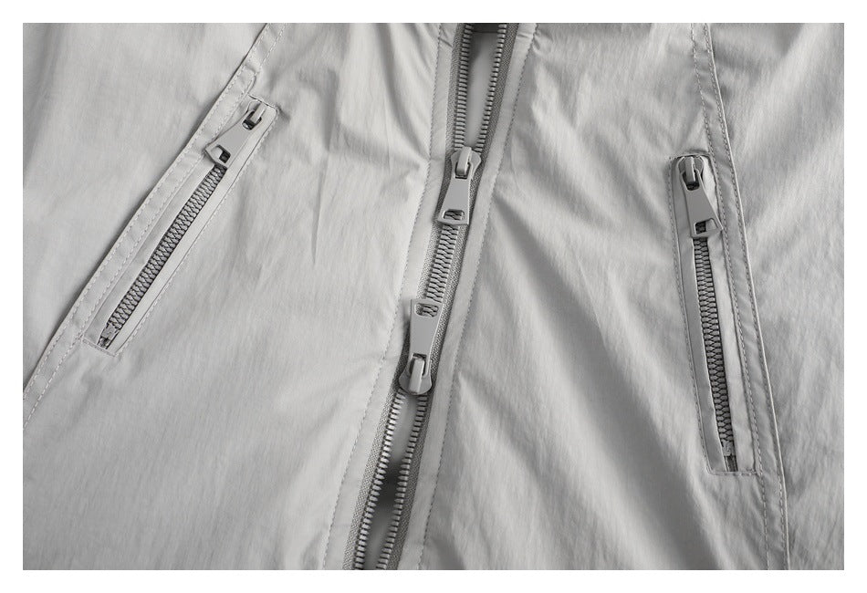 Close-up detail of a light gray jacket showing the center zipper and two slanted zip pockets.