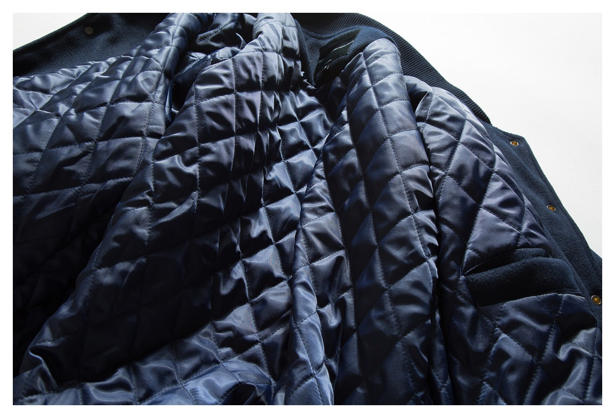 Close-up of a navy coat opened to show its shiny diamond-quilted lining and snap fasteners.
