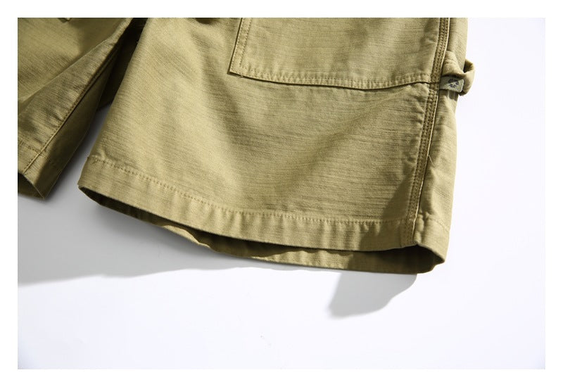 Close-up of the khaki shorts' hem and lower pocket edge against a white background.