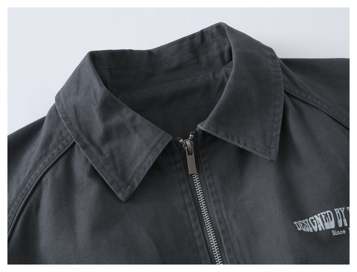 Close-up of a charcoal jacket collar and front zipper, with part of a white chest print visible.