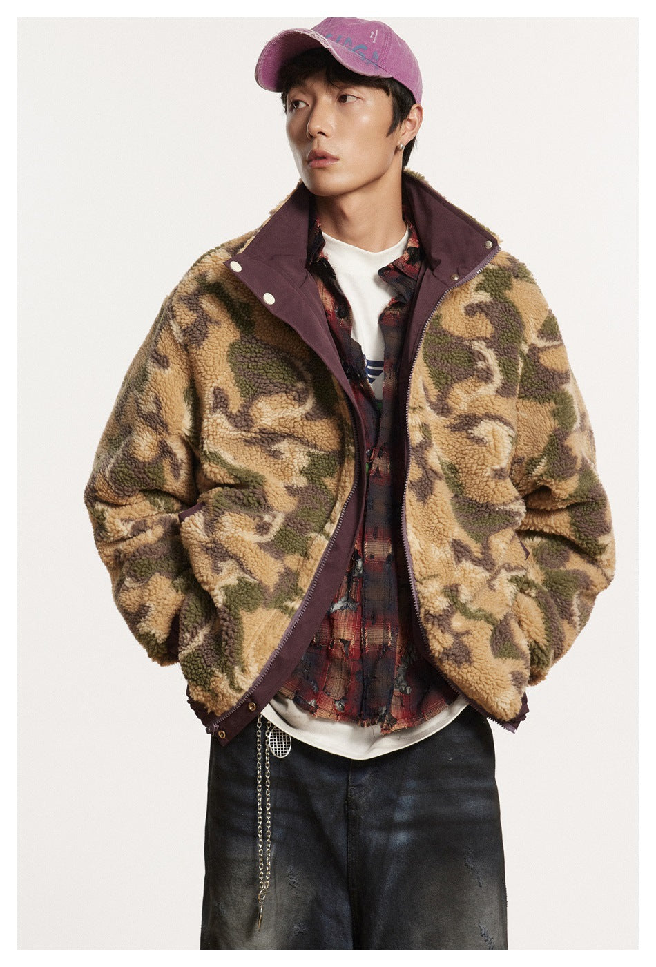 Front view of a model wearing an open camouflage fleece jacket with plum trim and dark jeans.
