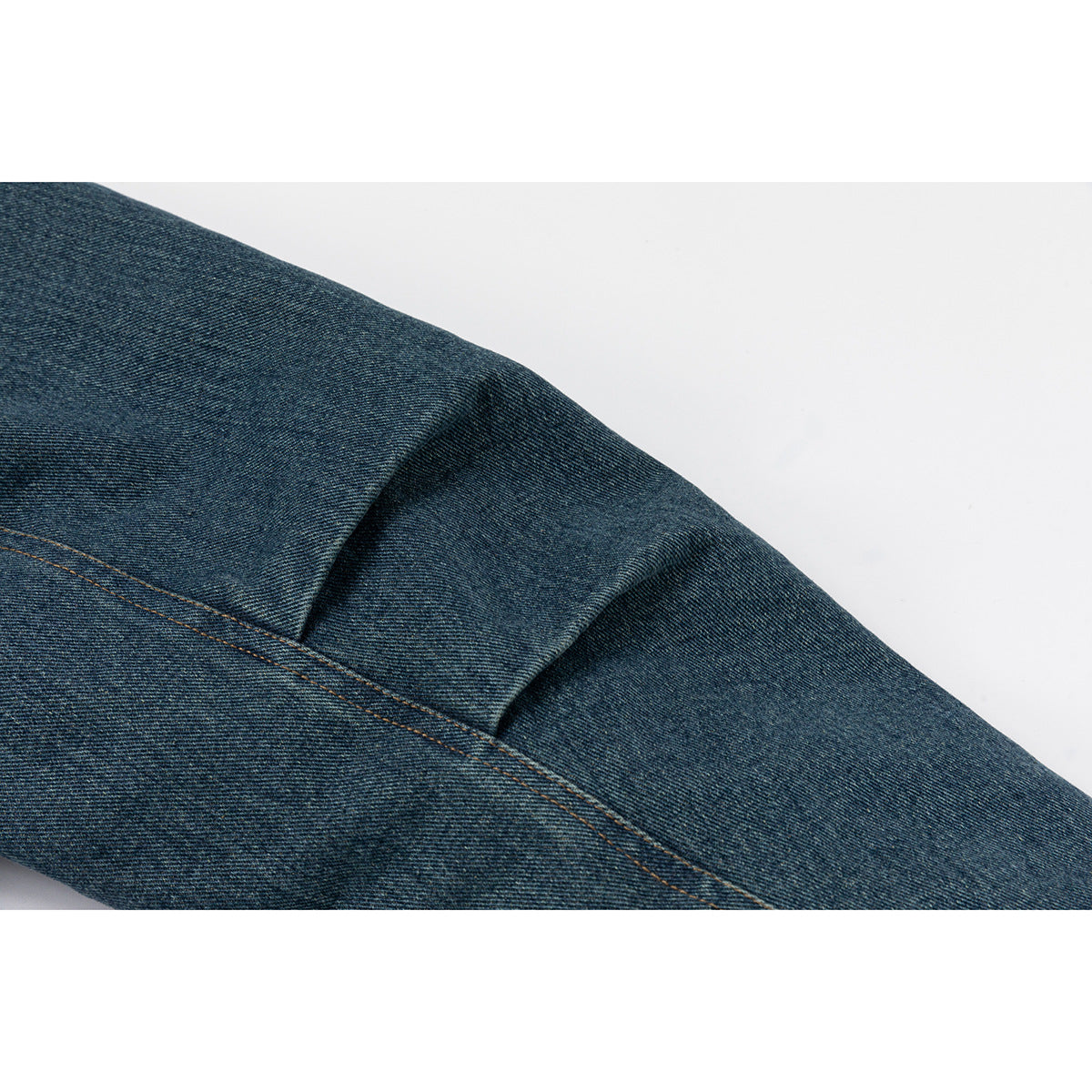 Close-up of the blue denim sleeve showing a folded seam and contrasting stitching.