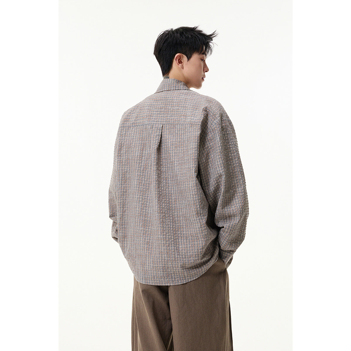 Back view of a model wearing a loose gray blue-and-tan checked shirt with a center back pleat.