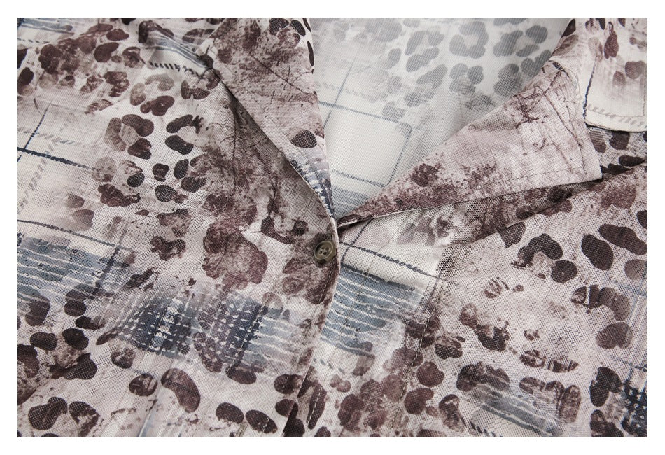 Close-up of the shirt's collar, button, and abstract brown, gray, and blue print.