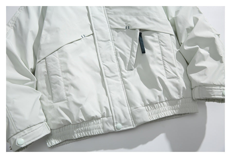 Close-up of the white jacket's front pockets, snap-fastened placket, and elasticized hem.