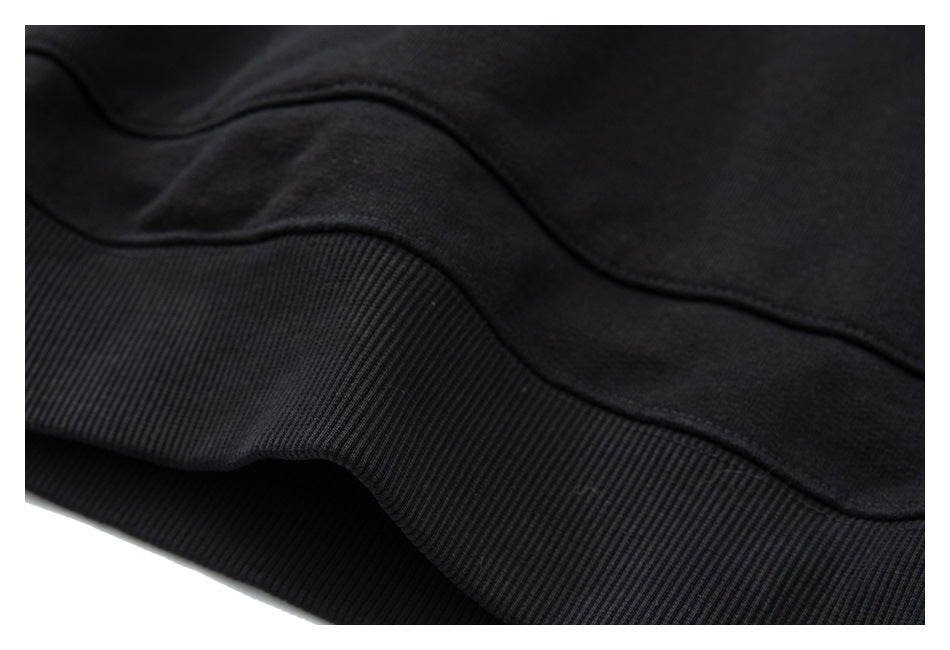 Close-up of the black hoodie’s ribbed hem and curved seam.