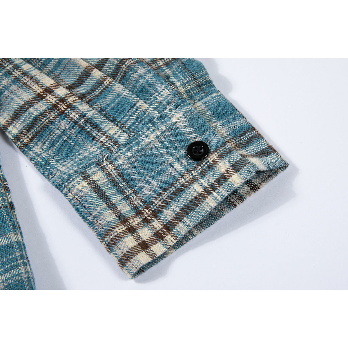 Close-up of a buttoned cuff on a blue, cream, and brown plaid shirt.