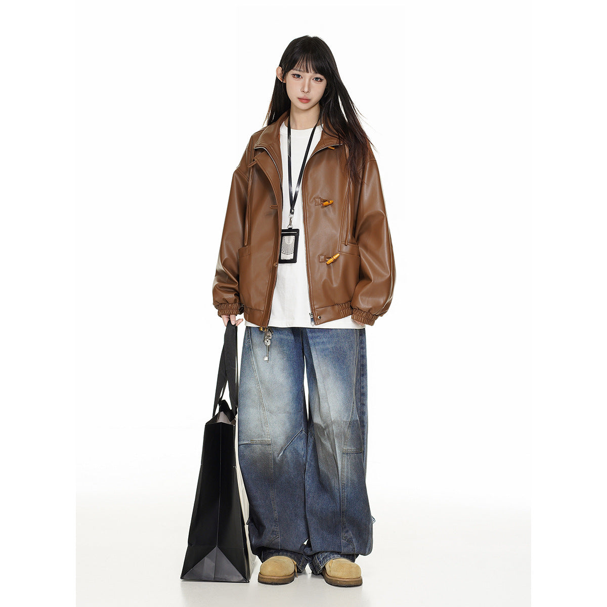 Model wearing an oversized brown jacket with wide lapels and gathered cuffs, styled with a white top and loose blue jeans.