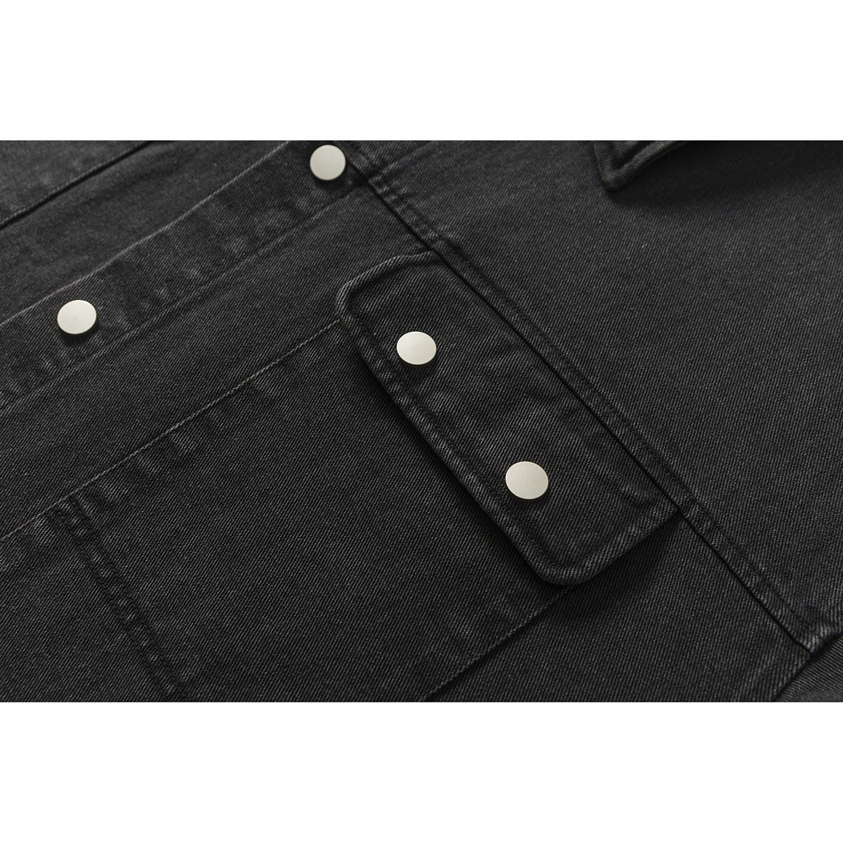 Close-up of a black denim jacket front pocket flap and silver snap buttons.
