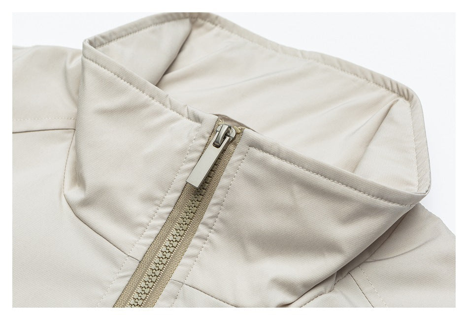 Close-up of a light beige jacket's raised collar and front zipper.