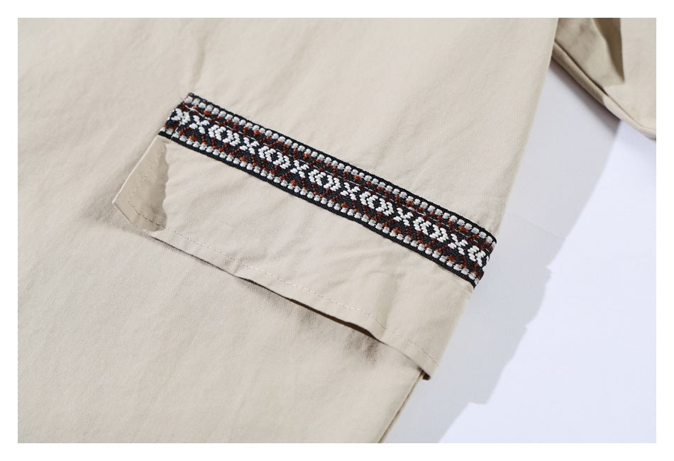 Close-up of a beige shirt sleeve cuff with black, white, and rust geometric trim.