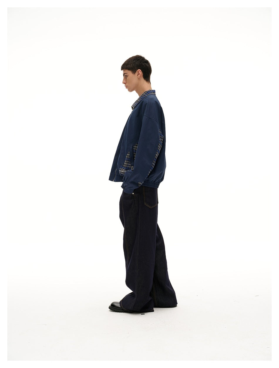 Side view of model wearing navy zip jacket with plaid side panels and elastic hem, with wide dark jeans