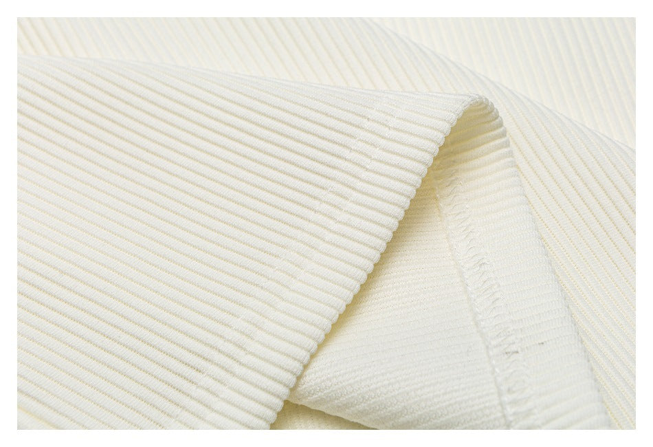 Close-up of ivory ribbed knit fabric folded to show its textured edge and stitching.