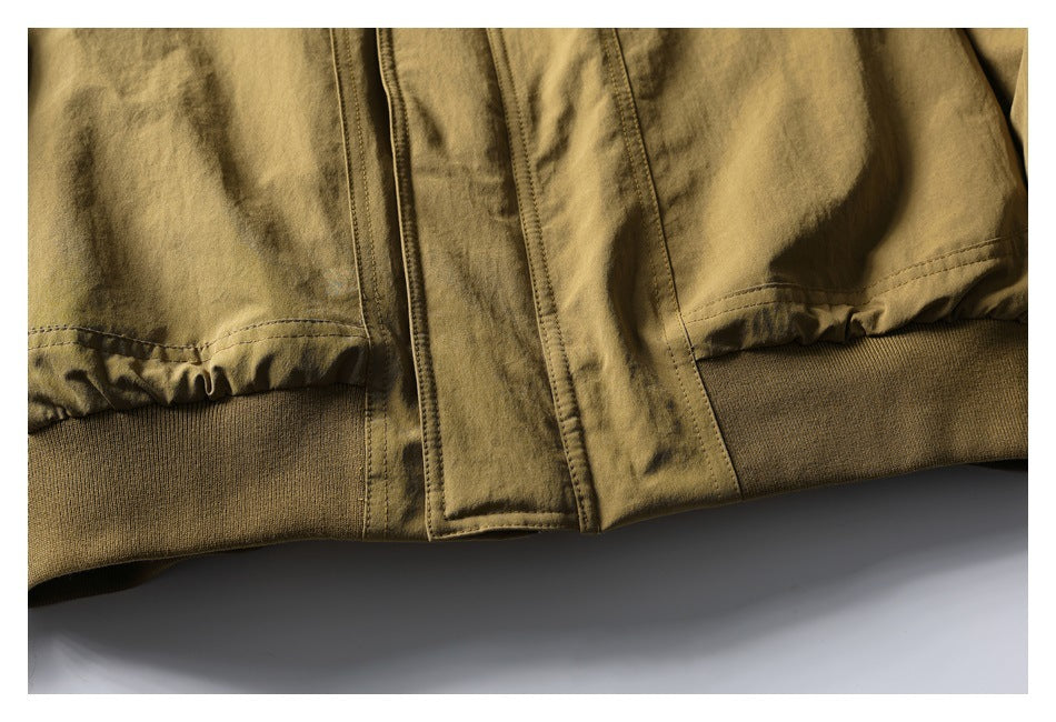 Close-up of a tan olive jacket's front placket and gathered lower hem with ribbed waistband.