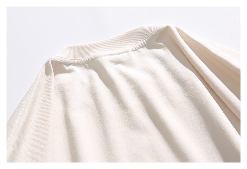 Close-up of the ribbed crew neckline and shoulder seam of an ivory T-shirt.
