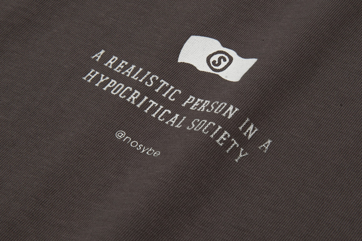 Close-up of a dark brown shirt with a white emblem and slogan printed across the fabric.