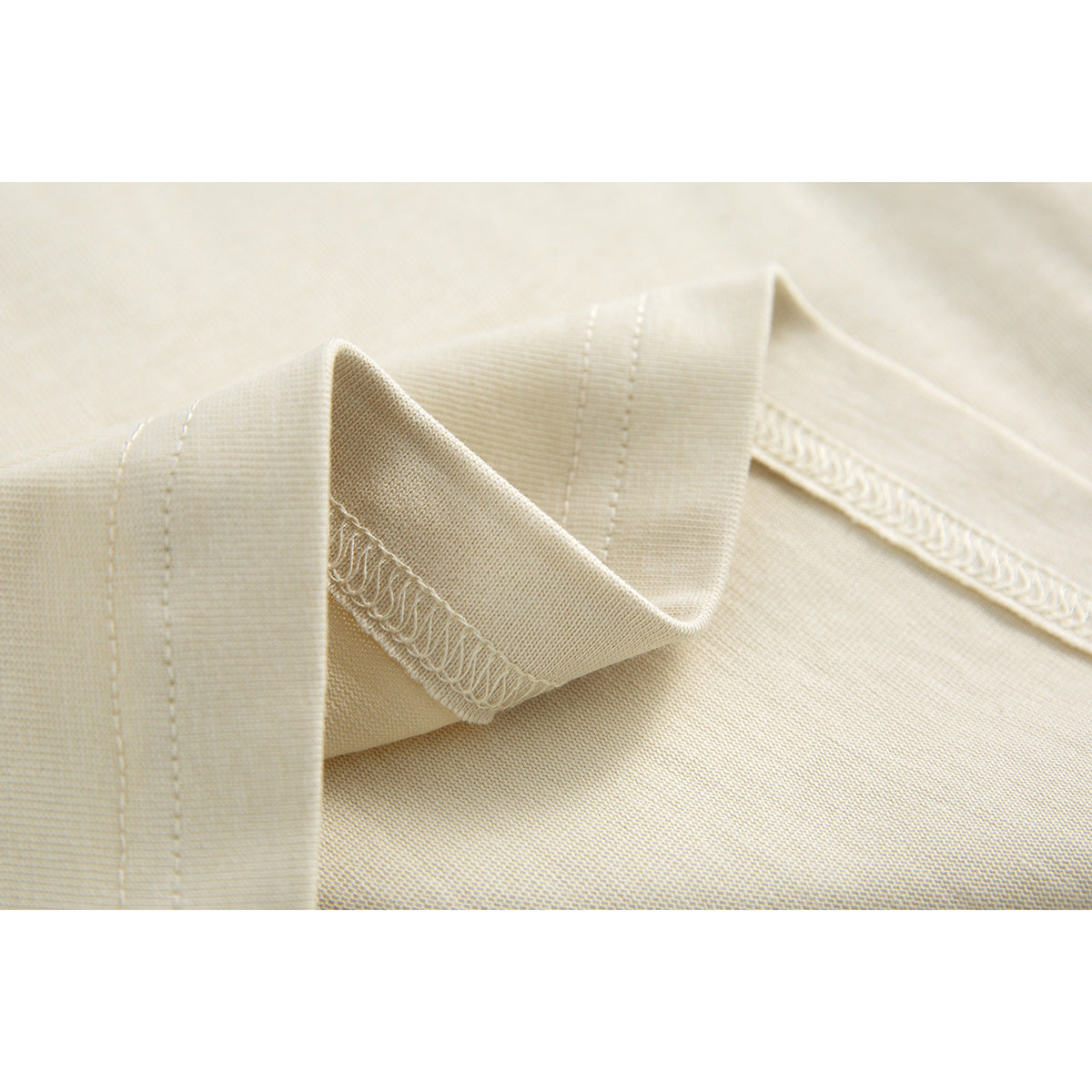 Close-up of cream shirt neckline stitching, ribbed collar, and inner seam finishing.