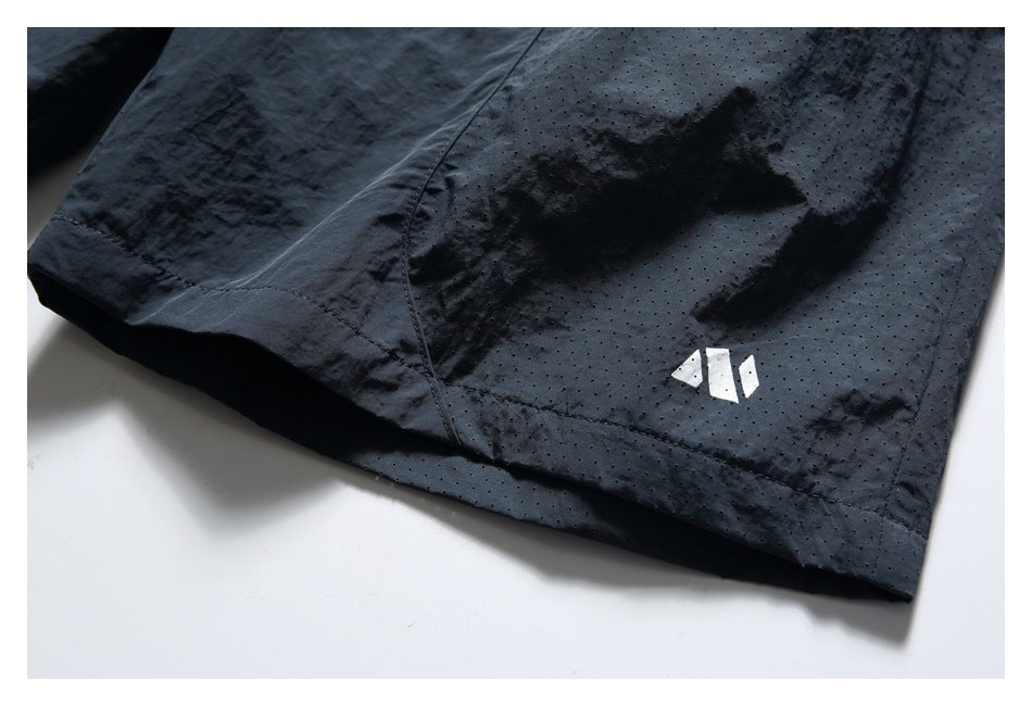 Close-up of a navy shorts leg hem with perforated fabric and a small white garment logo.