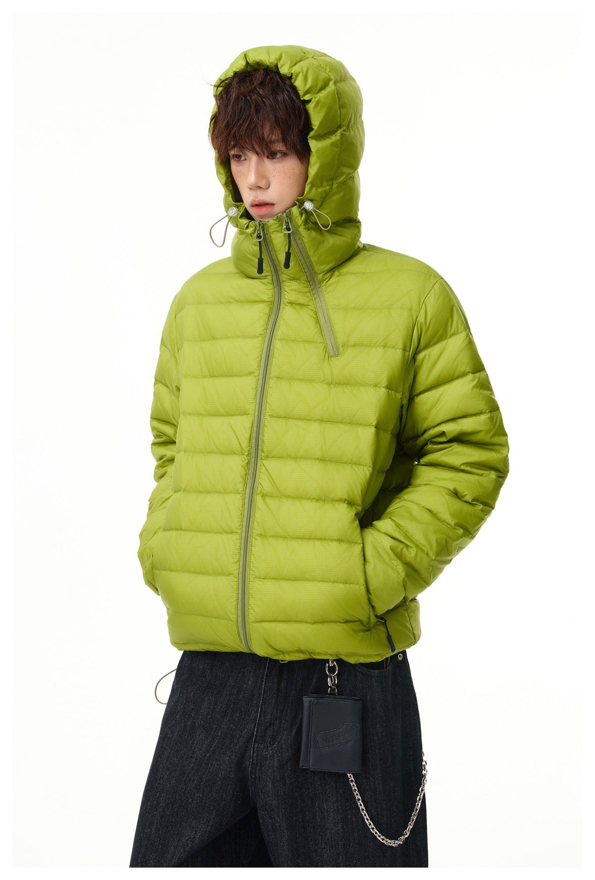 Model wearing a lime-green hooded quilted jacket with an asymmetric front zipper and dark jeans.
