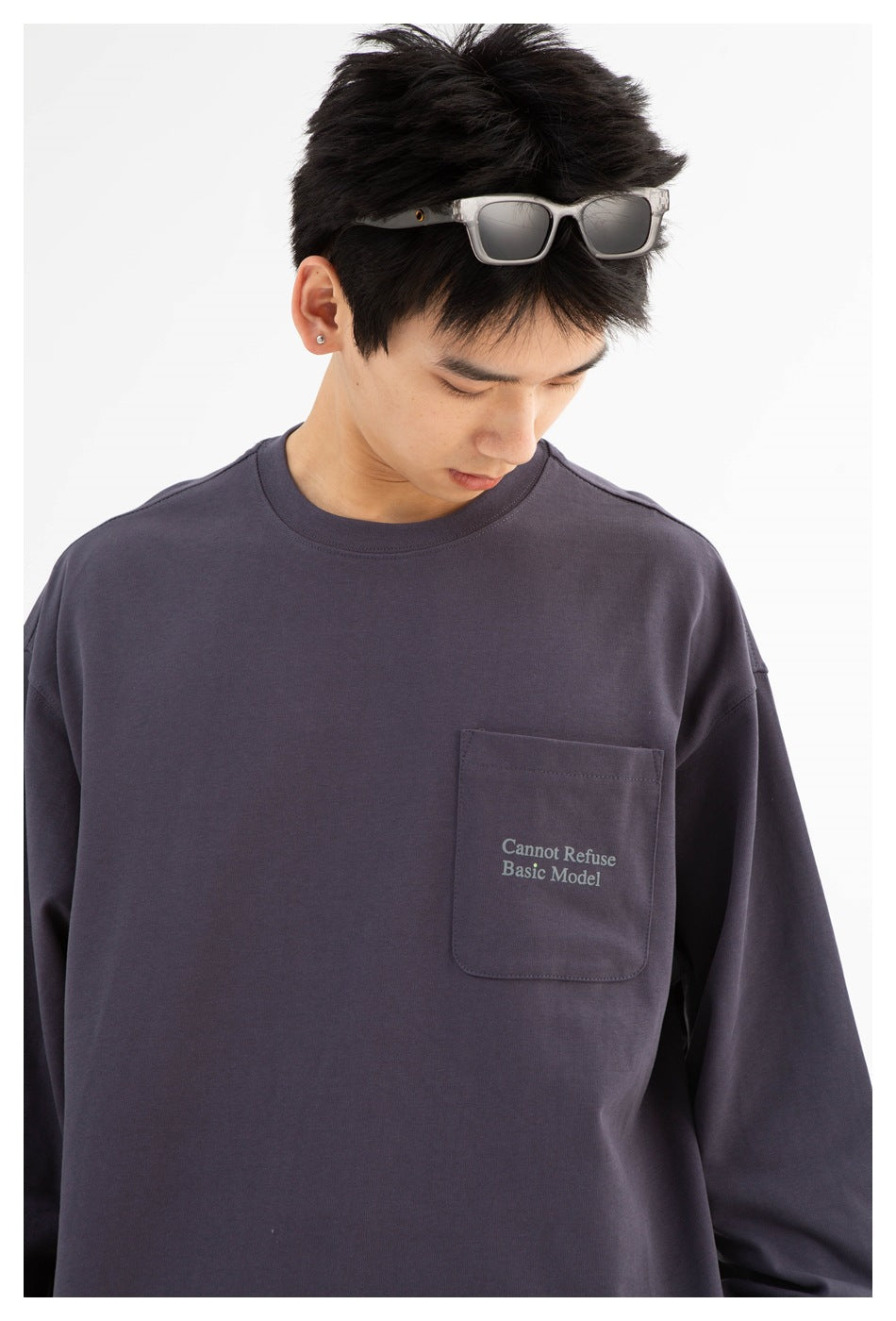 Model wearing a charcoal-gray oversized long-sleeve crewneck shirt with a chest pocket and small English text.