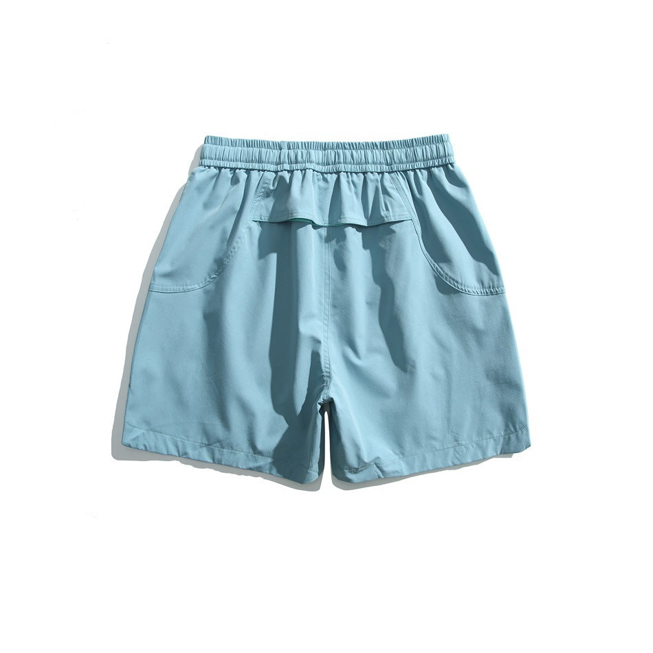 Pale blue athletic shorts shown from the back, with an elastic waistband, flap pocket, and curved side pockets.
