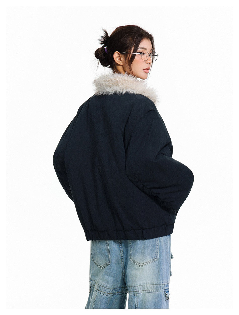 Rear view of a model wearing a black cropped jacket with a cream faux-fur collar.