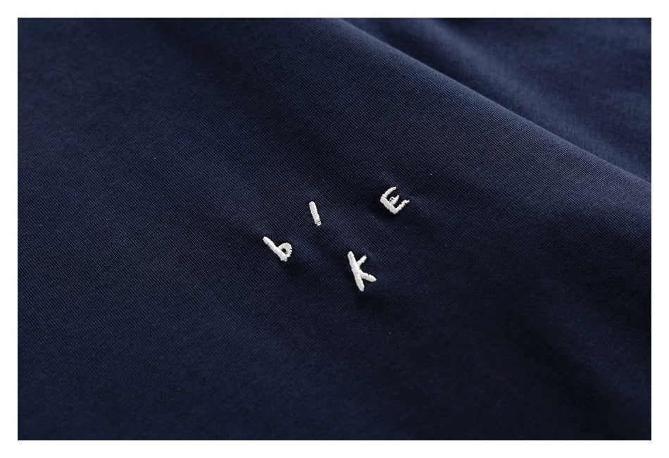 Close-up of small white embroidered letters on dark navy fabric.
