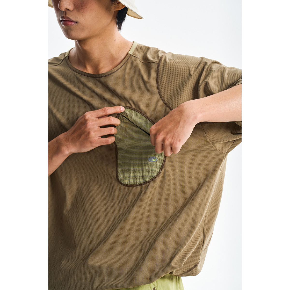 Close-up of a tan short-sleeve top as a model demonstrates its large patterned chest pocket.
