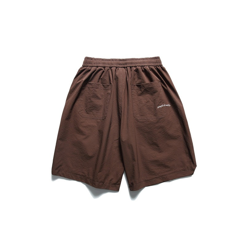 Back view of dark brown shorts with an elastic waistband, two patch pockets and small white script near one pocket.