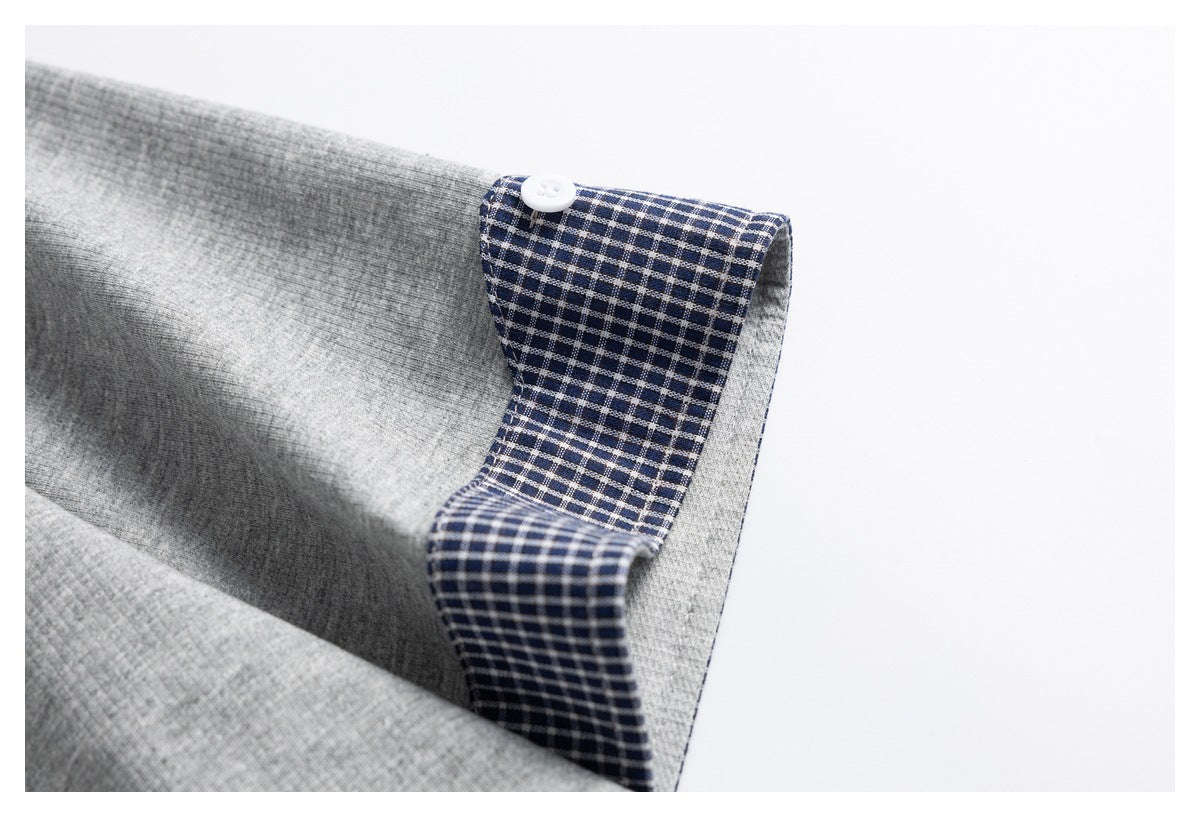 Close-up of a gray garment with a navy-and-white checked facing and a white button.