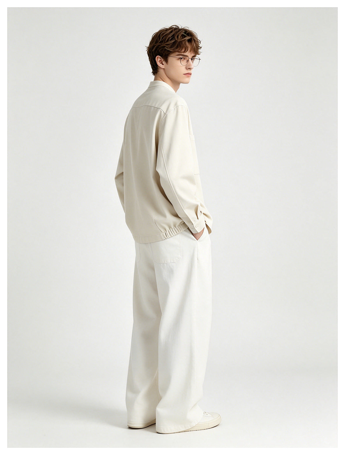 Model in the beige shirt jacket with white wide trousers, side-back view showing elastic gathered hem
